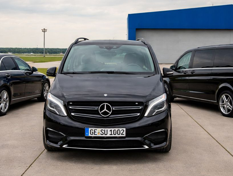 Ein schwarzer Mercedes Van steht auf einem Parkplatz vor einem blauen Gebäude